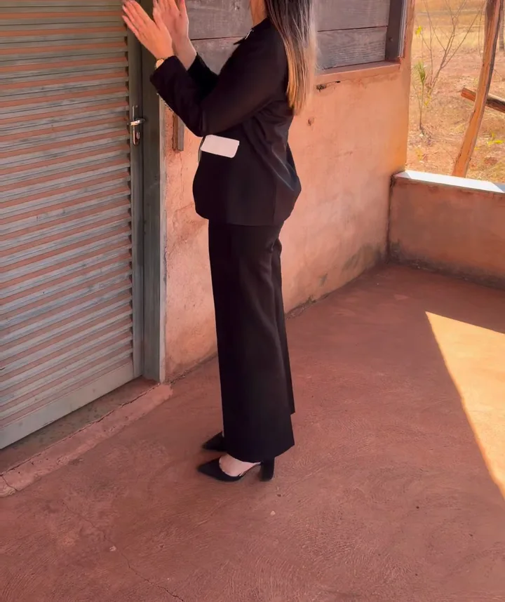Dra. Laiane chegando à varanda da casa e batendo palmas diante da porta.